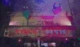 a group of people are dancing on a stage in front of a crowd in a club .