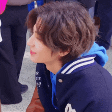 a close up of a person 's face with a blue jacket that says ' de ' on it
