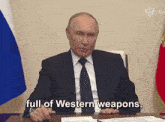 a man in a suit and tie is sitting at a desk and saying full of western weapons