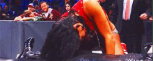 a female wrestler is laying on the ground during a wrestling match while a crowd watches .