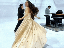 a woman in a white dress dancing in front of a piano