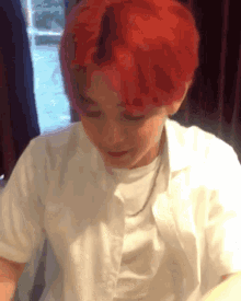 a person with red hair is wearing a white shirt and a necklace