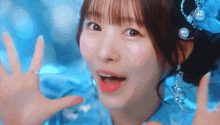 a girl in a blue dress with pearls on her head is making a funny face