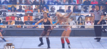 two women are wrestling in a ring with a referee watching .