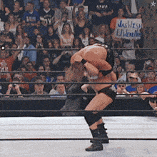 a man in a wrestling ring holds a sign that says jaswish underneath him