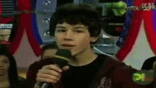 a young man is holding a microphone in front of a crowd of people .