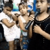 a girl is singing into a microphone while standing next to two other girls .