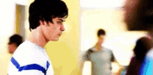 a man in a blue and white striped sweater is standing in a room with other people .