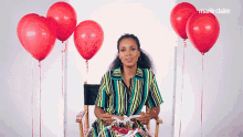 a woman is sitting in a chair surrounded by red balloons and marie claire