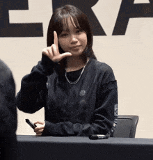 a girl in a black shirt with the word era on the sleeve is giving the middle finger