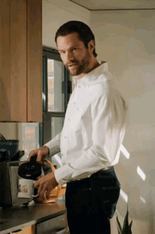 a man in a white shirt is pouring a cup of coffee