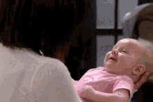 a woman is holding a baby in her arms and it is crying .
