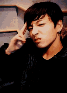 a young man with short hair is wearing a black shirt and earrings