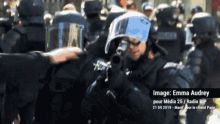 a police officer is holding a rifle in front of a crowd of people