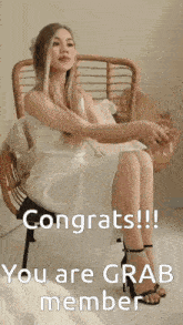a woman in a white dress is sitting in a wicker chair with the words congrats you are grab member