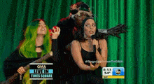 a group of women are standing in front of a green curtain on a stage .
