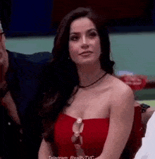 a woman in a red strapless top is sitting in front of a table .