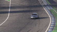 a silver car is driving down a road with a red and white striped curb