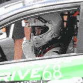 a person wearing a helmet is sitting in a car with the number 68 on the side