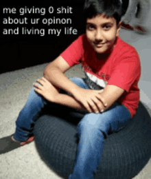 a boy in a red shirt is sitting on a black bean bag chair