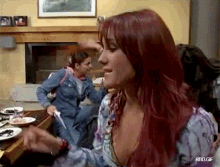 a woman with red hair is sitting in front of a fireplace