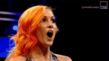 a woman with orange hair is standing in a dark room with her mouth open .