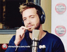 a man wearing headphones is talking into a microphone with a disney logo in the background