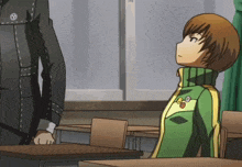 a boy in a green and yellow jacket with the letter o on it sits in a classroom