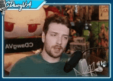 a man in a green shirt is sitting in front of a microphone in front of a sign that says avpwbo