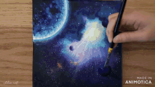 a person is painting a galaxy with the words made in animotica below them