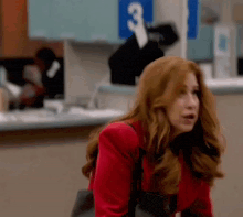 a woman in a red jacket is standing in front of a counter with a purse .