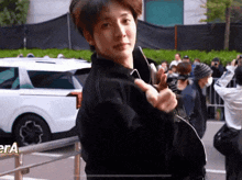 a man in a black jacket is giving a thumbs up in front of a white car and a sign that says cia
