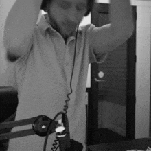 a man wearing headphones is standing in front of a microphone in a black and white photo