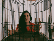 a woman is in a bird cage with gifsdayrol written on the bottom right