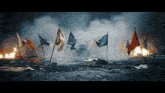 a row of flags are flying in the wind in front of a burning building