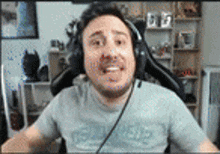 a man wearing headphones is sitting in front of a computer screen .