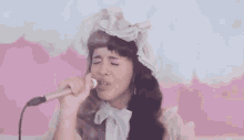 a girl is singing into a microphone while wearing a hat .