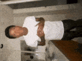a young man is standing in a room with his hands on his chest .
