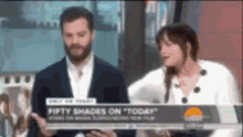 a man and a woman are standing next to each other in front of a sign that says fifty shades on today