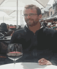 a man sitting at a table holding a glass of wine