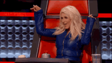 a woman in a blue leather jacket is sitting in a red chair .