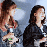 two women standing next to each other with one holding a bottle of water