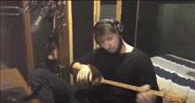 a man is playing a guitar in front of a microphone