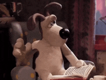 a cartoon dog is reading a book and giving a thumbs up