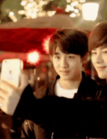 two young men are taking a picture of themselves with their cell phones