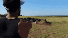 a man in a black tank top is standing in a field with the letter m on his back