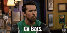 a man wearing a green shirt and a black jacket says go bats