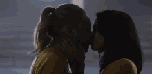 two women are kissing each other in front of a sign that says g2 .
