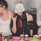a woman wearing a chef 's hat is making a devil horns sign while sitting at a table .