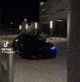 a black car is parked in a parking lot next to a building and a sign that says tik tok